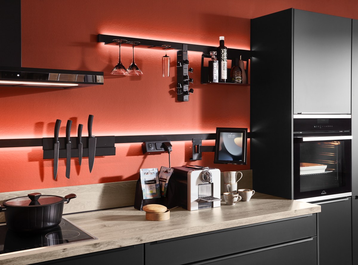 Sign Emotion Relingsystem Sign Emotion in Schwarz mit LED-Hinterleuchtung, Magnet-Messerhalter, Glashalter und Tablet-Halterung an einer korallenroten Wand