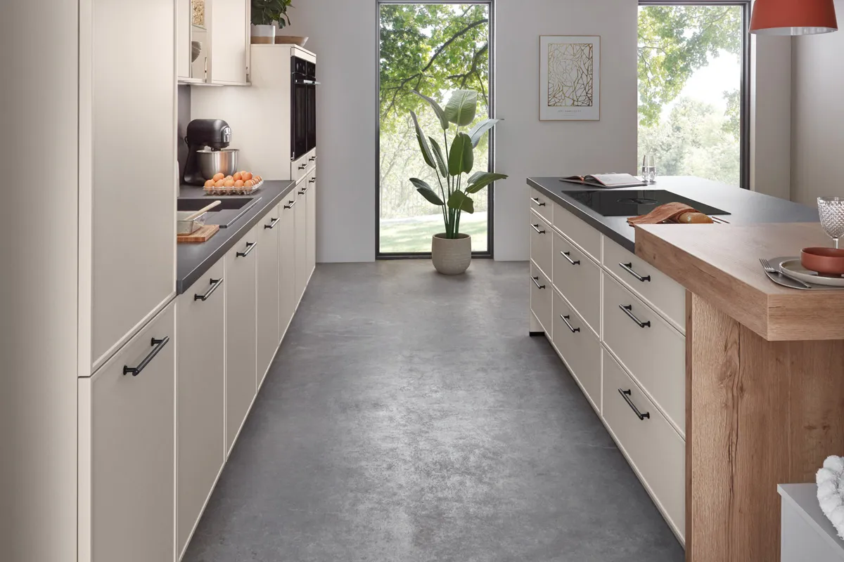 Blick durch die Küche in Sand mit schwarzen Bügelgriffen und Theke in Holzoptik